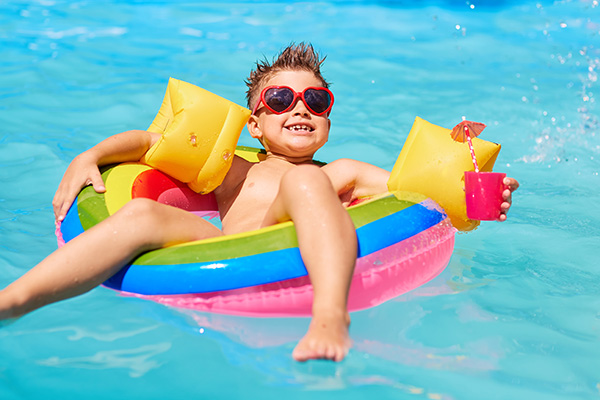 Junge mit Getränk und Sonnenbrille im Schwimmreifen