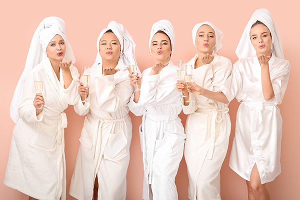 Gruppe von fünf Frauen mit Sekt im Bademantel