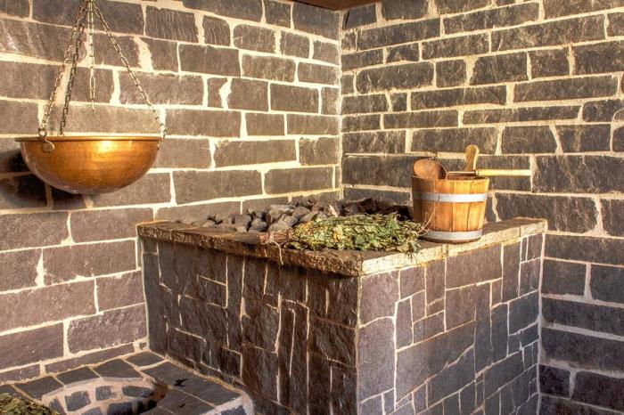 Saunaofen mit Holzeimer und Reisigbündel in der Reisigsauna